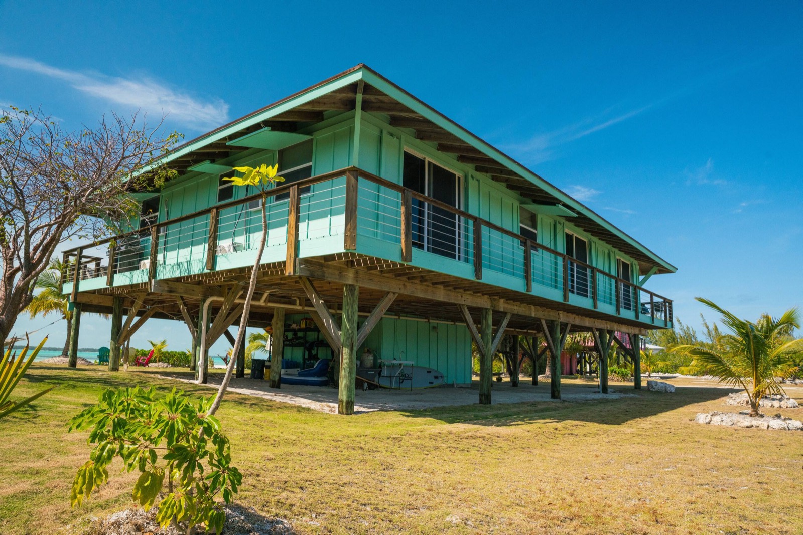 The villa on its pilings against a deep blue afternoon sky, a sliver of turquoise sea on the horizon