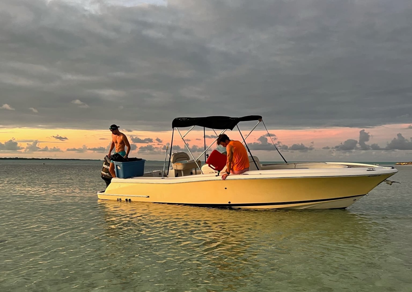 The Chris-Craft at anchor on glassy water at sunset, being loaded for an evening trip