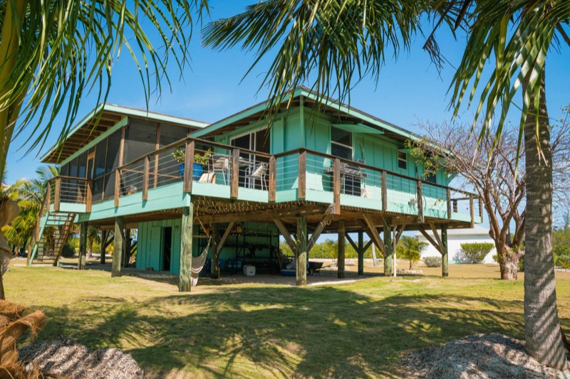 The raised villa framed by palm fronds, hammock slung between the pilings