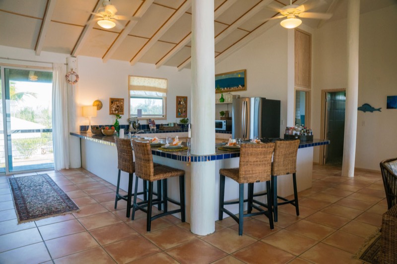 Open kitchen with a cobalt-tiled breakfast bar and four wicker barstools