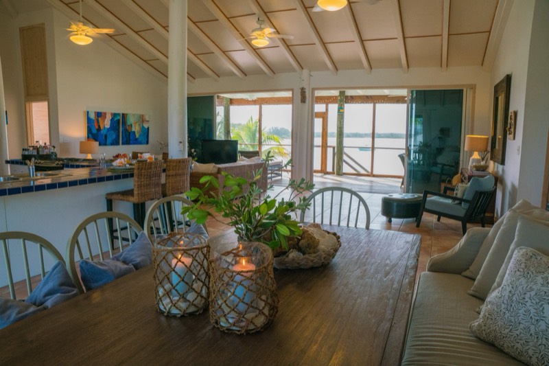Open-plan view from the dining table past the kitchen bar to the screened porch and the water