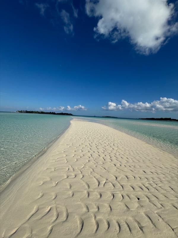 A rippled white sandbar stretching into turquoise water at low tide